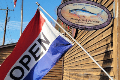Herring Creek Furniture Fish Sign at Old Cecil's Mill, REd, white, and blue Open flag flying in front of it