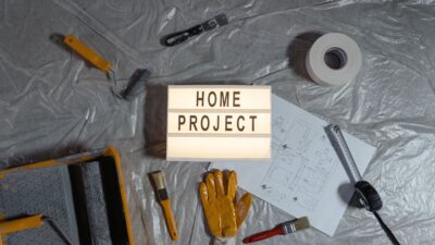 Home improvement project sign on a tarp surrounded by various tools.