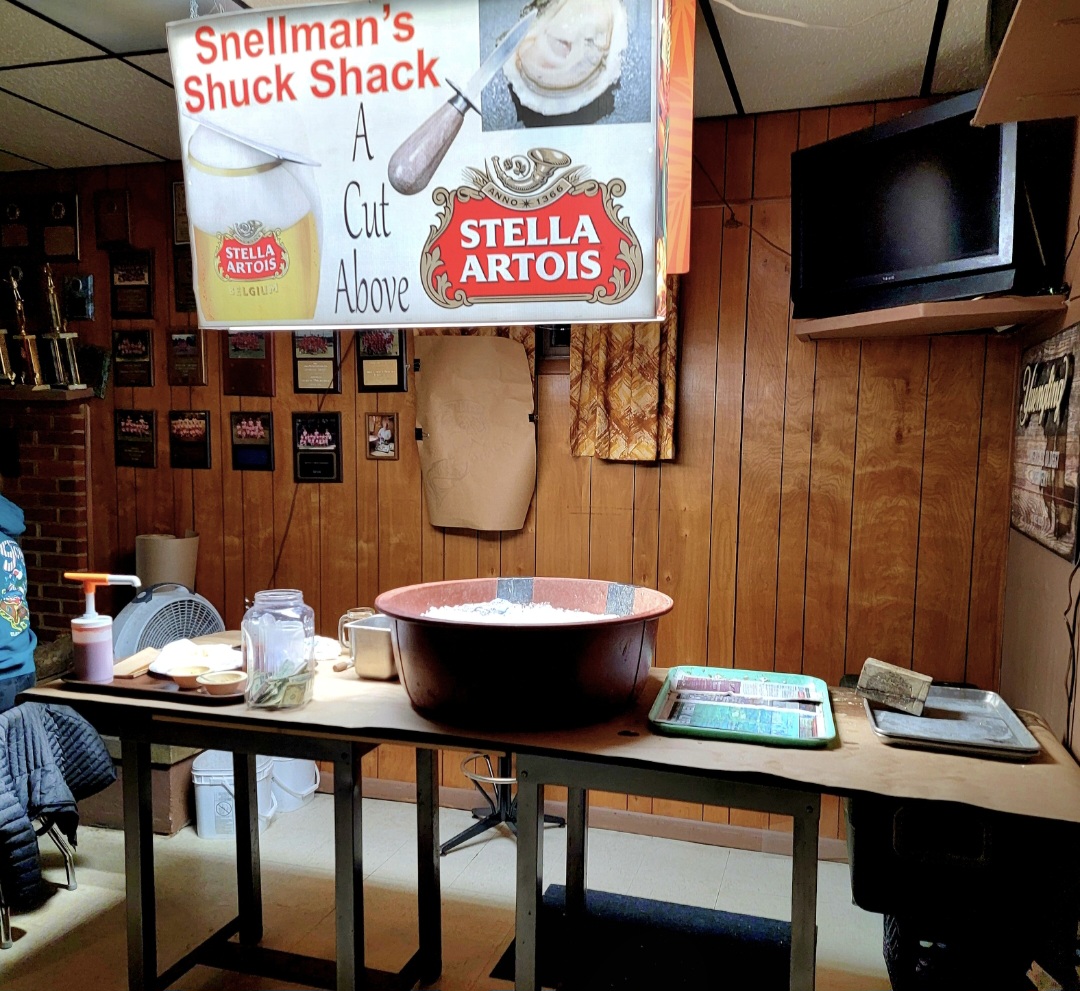 Shellman's Shuck Shack Sign Above Red Ice Bucket on a Wooden Table